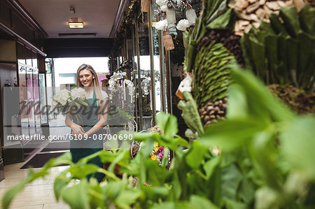 Portrait of female florist holding bunch of flowers at her flower shop