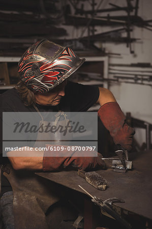 Blacksmith working on a metal piece in workshop