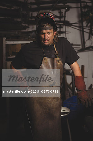 Portrait of blacksmith standing in workshop