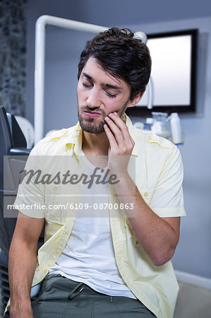 Unhappy man having a toothache in clinic