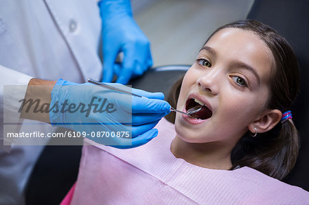 Dentist examining a young patient with angle mirror in dental clinic