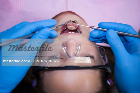 Dentist examining a young patient with tools at dental clinic