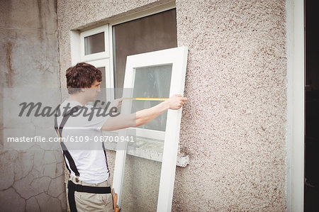 Carpenter measuring a door outside home