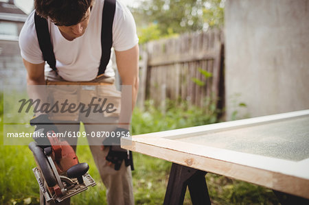 Carpenter working with circular saw outside a house