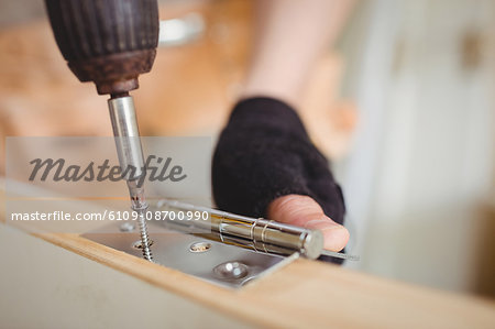 Carpenter tightening screw to hinges on a wooden door on a wooden door at home