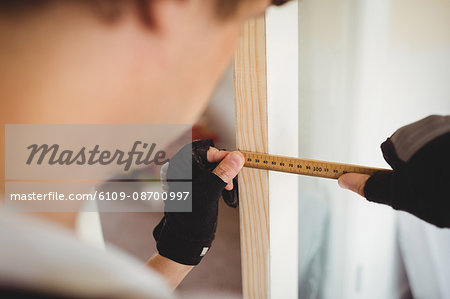 Carpenter measuring a wooden door at home