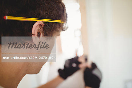 Carpenter with pencil on his ear while working at home