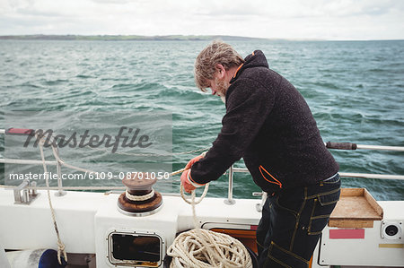 Fisherman tying rope on bollard in boat