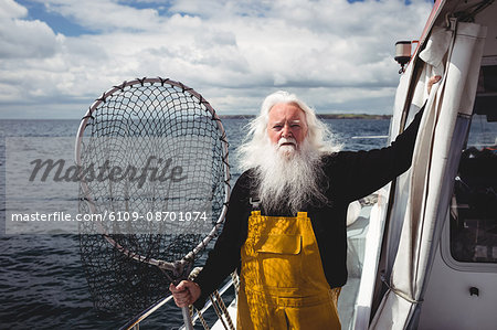 Portrait of fisherman holding fishing net on boat