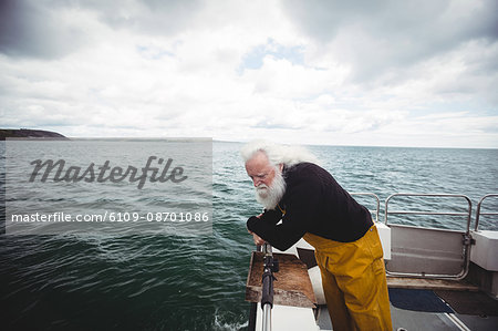 Fisherman looking into the sea from fishing boat