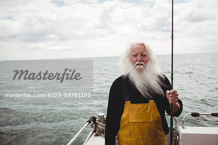 Portrait of fisherman standing on boat holding fishing rod