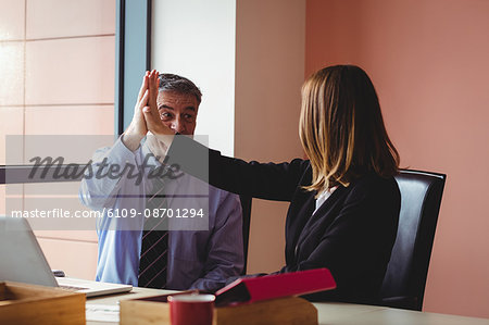 Businessman and businesswoman giving a high five in office