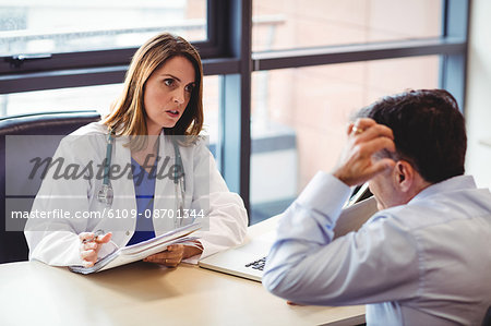 Female doctor at her desk talking to patient in the hospital