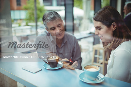 Man and woman discussing over mobile phone in the cafeteria
