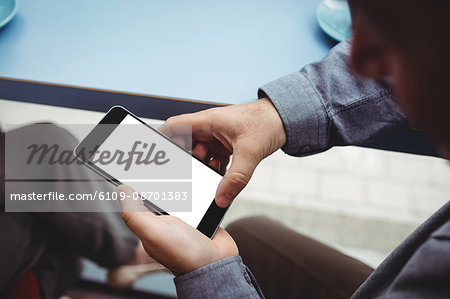 Close-up of man text messaging on mobile phone in cafeteria