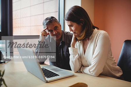 Man and woman discussing over laptop in the office