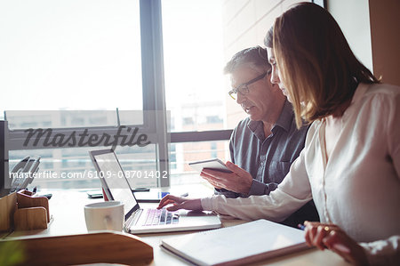 Man and woman discussing over digital tablet and laptop in the office