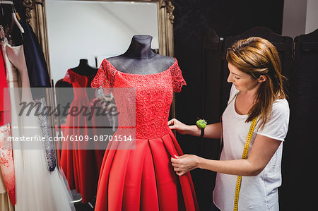 Creative designer adjusting the dress on a mannequin