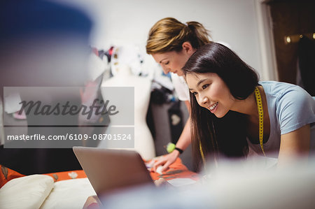 Female fashion designer working on laptop in the studio
