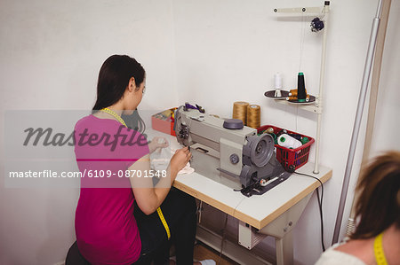 Female dressmaker sewing on the sewing machine in the studio