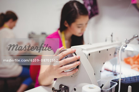 Female dressmaker sewing on the sewing machine in the studio