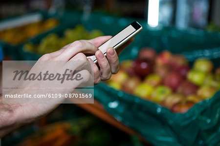 Man using mobile phone while shopping in supermarket