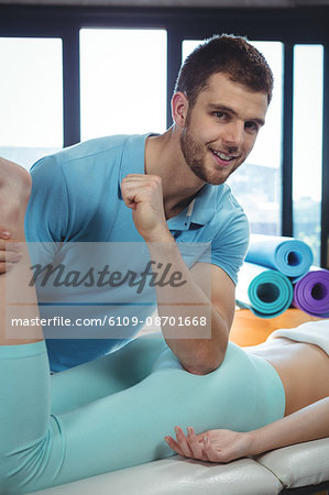 Male physiotherapist giving hip massage to female patient in clinic