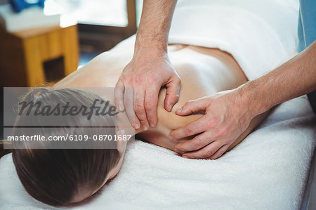 Physiotherapist giving physical therapy to the shoulder of a female patient in the clinic