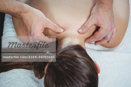 Close-up of physiotherapist giving physical therapy to the back of a female patient in the clinic