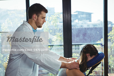 Physiotherapist giving back massage to a female patient in the clinic