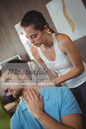 Female physiotherapist examining neck of a male patient in the clinic