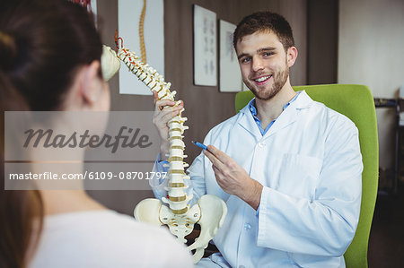 Portrait of physiotherapist explaining the spine to female patient in the clinic