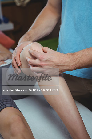 Physiotherapist giving physical therapy to the knee of a female patient in the clinic