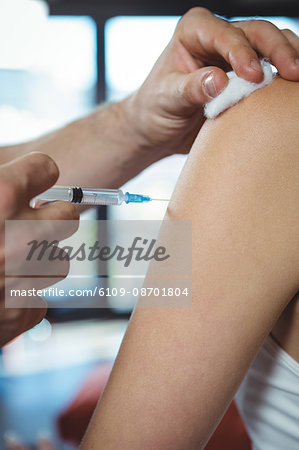 Close-up of female patient receiving injection from physiotherapist in the clinic