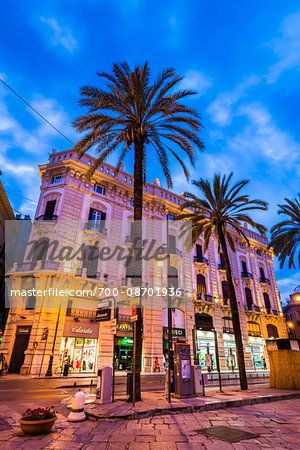 Ornate architecture and street corner along Via Roma in the shopping district at dusk, in the historic city of Palermo in Sicily, Italy