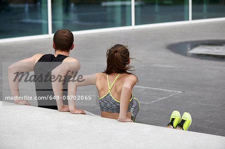 Young woman and man training, doing push ups against wall