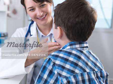 Doctor checking for swollen glands on boy's neck