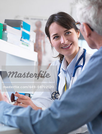 Doctor sharing health information on digital tablet with patient in clinic