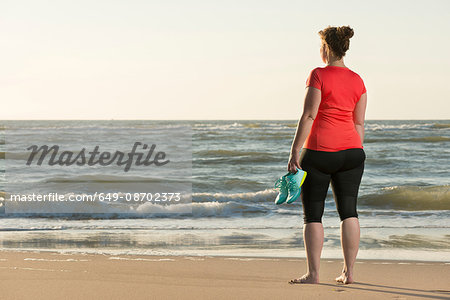 Mature woman standing on beach at sunset, after running