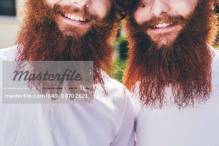 Cropped portrait of young male hipster twins with red beards wearing white tshirts