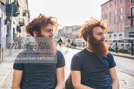 Young male hipster twins with red hair and beards on city street