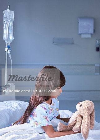 Girl patient gazing at toy rabbit on hospital children's ward