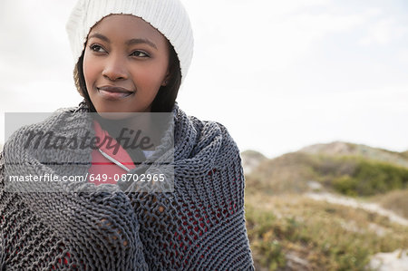 Young woman wrapped in knitted shawl on cold day