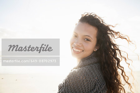 Young woman wrapped in knitted shawl on cold windy day