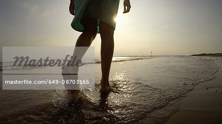 Legs of woman on coastline walking in ocean