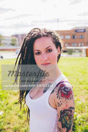 Portrait of tattooed young woman in urban park
