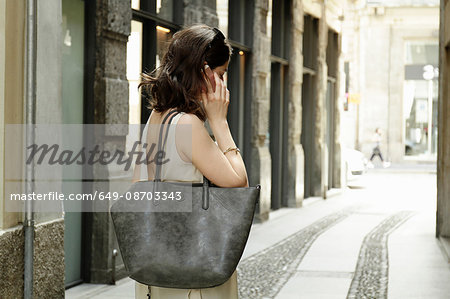 Woman using smartphone on traditional street, Milan, Italy