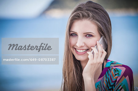 Beautiful young woman talking on smartphone at beach, Costa Rei, Sardinia, Italy