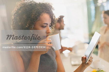 Businesswoman drinking coffee and using digital tablet