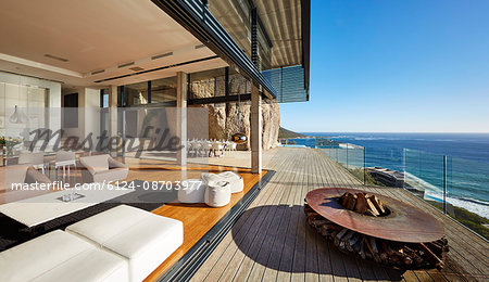 Fire pit and furniture on modern luxury beach house patio with sunny ocean view